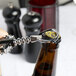 A black Franmara Tavern Wing Corkscrew opening a bottle of beer on a counter.