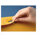A person's hand opening a brown Kraft Quality Park file envelope.