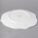 A white Villeroy & Boch bone porcelain plate with a small flower design on a gray surface.