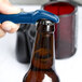 A hand using a dark blue Franmara Traveler's plastic bottle opener to open a brown bottle.