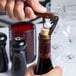 A person using a Laguiole waiter's corkscrew with a rosewood handle to open a wine bottle.