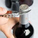 A person using a Laguiole Waiter's Corkscrew with a rosewood handle to open a bottle of wine.
