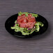 A black Elite Global Solutions Ming melamine plate with raw tuna and lettuce on it.