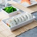 A sushi roll with salmon and rice in a white rectangular ramekin.