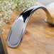 A Bon Chef stainless steel Tuscany soup/dessert tasting spoon on a wooden surface.