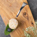 A Bon Chef Reflections spoon with food on it on a wooden surface.