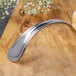 A Bon Chef sombrero bouillon tasting spoon with a silver handle on a wood surface.