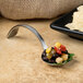 A Bon Chef stainless steel sombrero bouillon tasting spoon with food on it.
