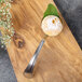 A Bon Chef stainless steel sombrero bouillon spoon with food on it on a wood surface.
