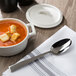 A bowl of soup with croutons and a Bon Chef stainless steel soup spoon on a napkin.