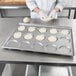 A person in a white coat making dough on a Chicago Metallic baking tray.