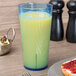 A Thunder Group blue polycarbonate tumbler filled with yellow juice on a breakfast table with a sandwich.