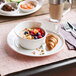A Villeroy & Boch NewWave white porcelain plate with a croissant, fruit, and a cup of coffee.