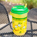A yellow lemonade in a green lidded plastic container.