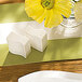 A close-up of a Villeroy & Boch NewWave white premium porcelain salt shaker on a table with a yellow flower.