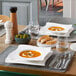 A table set with Villeroy & Boch NewWave porcelain plates, soup, bread, and utensils.