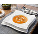 A Villeroy & Boch white porcelain pasta plate with a bowl of soup on it.