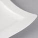 A close-up of a white Villeroy & Boch NewWave square porcelain plate with a curved edge.