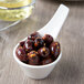 A Villeroy & Boch white porcelain dip bowl with a spoon full of olives.