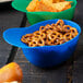 A blue bowl of pretzels and chips with a close up of chips.