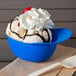 A blue mini baseball helmet bowl filled with ice cream and a cherry on top.