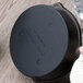 A black Lodge round magnetic trivet on a counter with a white towel on it.