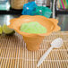 A bowl of green ice cream with a spoon on a bamboo mat.