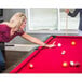 A woman playing pool on a red Mizerak Donovan II pool table with a stick.