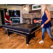 A man and woman playing table tennis on a Triumph Phoenix pool table with a red paddle.