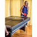A woman playing ping pong on a Triumph Phoenix pool table.