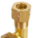 A brass threaded pipe fitting with a nut on a gold metal pipe.