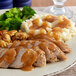 A plate of turkey, mashed potatoes, and Vanee Roasted Turkey Gravy with broccoli on the side.