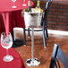 An American Metalcraft wine bucket stand with a wine bucket and bottle of wine on a table.