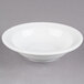 A Libbey alpine white porcelain fruit bowl with a rim on a gray surface.