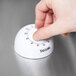 A hand turning on a Taylor 5832 mechanical kitchen timer.