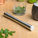 A Tablecraft stainless steel muddler with a tenderizer head muddling lime and mint in a glass.