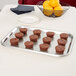 A Vollrath stainless steel serving tray with brownies on a table.