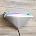 A triangular stainless steel wall sconce with a white box of blue insect trap glue boards on a wood surface.