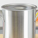 A Vollrath stainless steel stock pot cover on a stainless steel stock pot.