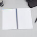 A TOPS wirebound narrow ruled notebook with an indigo cover on a desk with a pen.