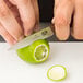 A person's hand using a Victorinox paring knife to cut a lime.