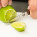 A person using a Victorinox paring knife to cut a lime.