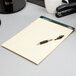 A TOPS Docket yellow notepad with wide lines and a pen on top.