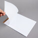 A hand holding a white wide ruled legal pad sheet.