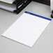 An Ampad wide ruled white notepad on a gray surface.