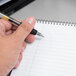 A hand holding a pen writes on a TOPS Docket Diamond planner pad.