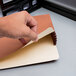 A person's hand holding a brown Pendaflex legal file pocket.