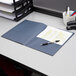 An Oxford dark blue paper pocket folder on a desk with paper and pens inside.