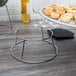 A Choice chrome plated steel display stand holding a tray of food on a table.