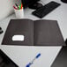 A black Oxford 2-pocket folder on a desk.